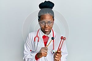 Young african american woman wearing doctor uniform holding tuning fork depressed and worry for distress, crying angry and afraid