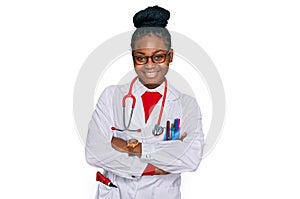 Young african american woman wearing doctor uniform and stethoscope happy face smiling with crossed arms looking at the camera