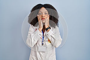 Young african american woman wearing doctor uniform and stethoscope tired hands covering face, depression and sadness, upset and