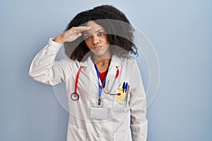 Young african american woman wearing doctor uniform and stethoscope worried and stressed about a problem with hand on forehead,