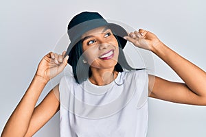 Young african american woman wearing fashion hat smiling looking to the side and staring away thinking