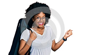 Young african american woman wearing guitar case screaming proud, celebrating victory and success very excited with raised arm