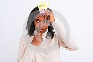 Young african american woman wearing pretend queen crown over isolated background serious face thinking about question, very