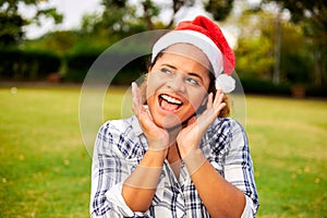 A young African-American woman wearing a Santa hat shows a surprised expression