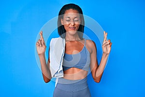 Young african american woman wearing sportswear gesturing finger crossed smiling with hope and eyes closed