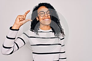 Young african american woman wearing striped sweater and glasses over white background smiling and confident gesturing with hand
