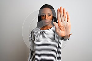 Young african american woman wearing striped t-shirt standing over isolated white background doing stop sing with palm of the hand
