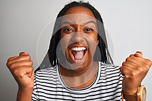 Young african american woman wearing striped t-shirt standing over isolated white background screaming proud and celebrating