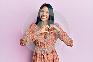 Young african american woman wearing summer dress smiling in love showing heart symbol and shape with hands