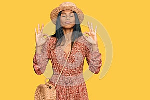 Young african american woman wearing summer hat relax and smiling with eyes closed doing meditation gesture with fingers