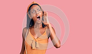 Young african american woman wearing summer outfit shouting and screaming loud to side with hand on mouth