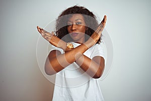 Young african american woman wearing t-shirt standing over isolated white background Rejection expression crossing arms doing