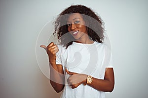 Young african american woman wearing t-shirt standing over  white background Pointing to the back behind with hand and