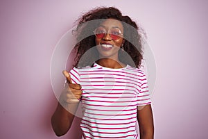Young african american woman wearing t-shirt and sunglasses over isolated pink background doing happy thumbs up gesture with hand