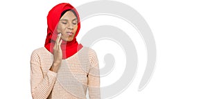 Young african american woman wearing traditional islamic hijab scarf touching mouth with hand with painful expression because of