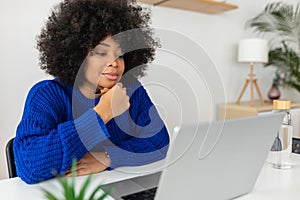 Young african american woman working on laptop at home.