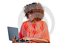 Young african american woman working using computer laptop thinking attitude and sober expression looking self confident