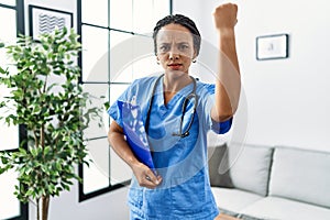 Young african american woman working wearing doctor uniform working at the clinic annoyed and frustrated shouting with anger,