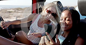 Young African American woman and young Caucasian woman enjoy a sunny day outdoors on a road trip