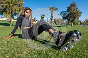 Young African-American women wearing roller skates sits on the grass
