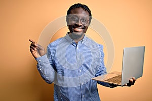 Young african american worker man working using laptop standing over yellow background very happy pointing with hand and finger to