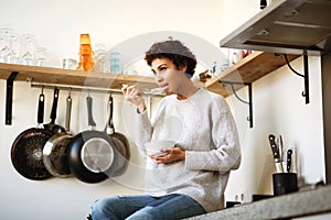 Young african americna woman eating cereal in kitchen at home photo