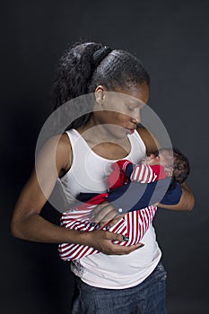 young African amrican young mother lovingly holding her newborn baby in her lap