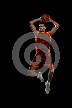 Young african basketball player training on black studio background.