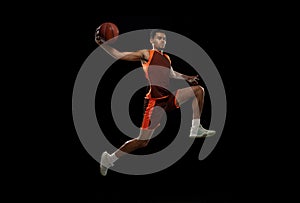 Young african basketball player training on black studio background.