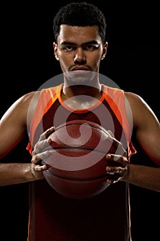 Young african basketball player training on black studio background.