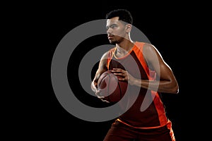 Young african basketball player training on black studio background.