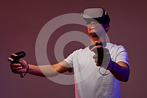 Young african boy with virtual reality glasses is playing a videogame, isolated in studio