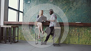 Young african businessman and caucasian businesswoman meeting at modern coworking space. Man and woman talking.