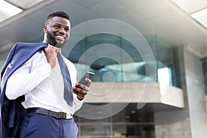 Young african businessman holding his phone while standing full of joy