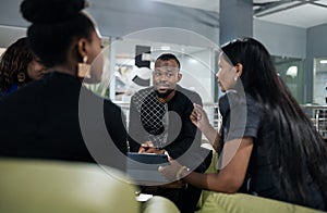 Young African businessman listening to colleagues during an office