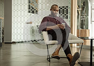 Young African businessman listening to music during his office break