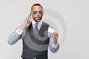 A young African businessman using his smartphone to shop online while holding his credit card