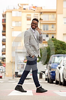 Young african businessman walking and talking on cell phone in the city