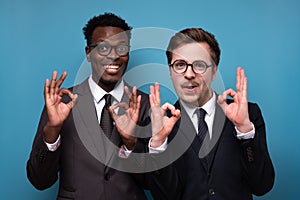 young african and caucasian business men showing OK gesture looking camera