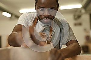 Young African ceramist sanding a clay pot at a studio bench