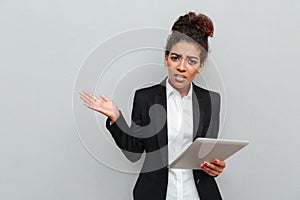 Young african confused business woman holding tablet computer.