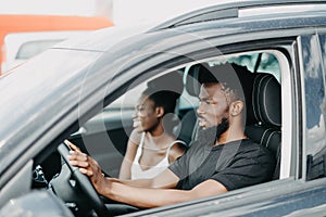 Young african couple in a car on a road trip smiling to camera