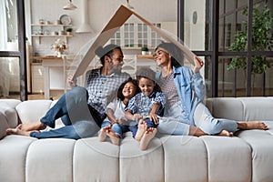 African family sit on couch under cardboard roof