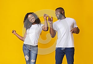 Young african couple dancing over yellow background