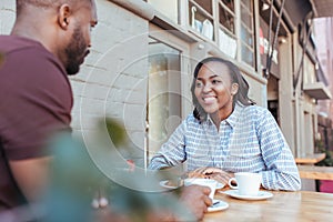 Young African couple talking together at a sidewalk cafe table