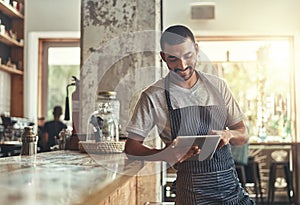 Young african entrepreneur using digital tablet in his cafe