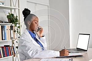 Young african female doctor physician holding phone talking on mobile at work.