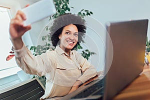 Young African female entrepreneur sitting at a desk in her home office make selfie photo