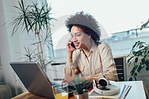 Young African female entrepreneur sitting at a desk in her home office working online with a laptop