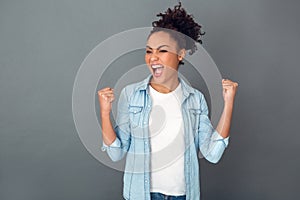 Young african woman isolated on grey wall studio casual daily lifestyle victory